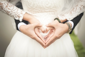 Wedding couple holding hands in heart shape.